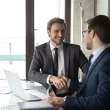 Smiling businessmen shake hands, commercial real estate broker services are an asset concept